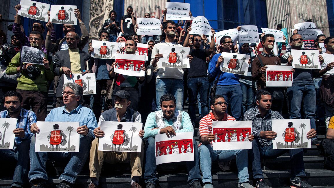 Journalists and photojournalists hold banners as they demonstrate in front of the journalist's syndicate in Cairo against repeated attacks on members of the press in Egypt on 4 April 2014. [Getty]